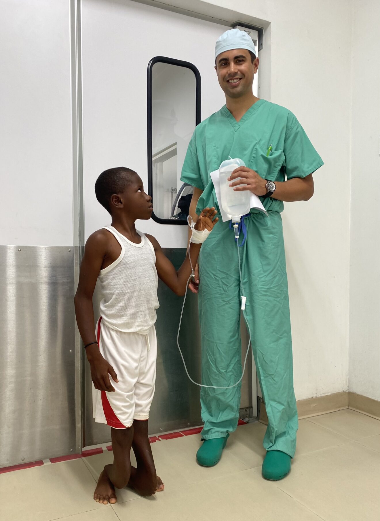 Doctor stands with a boy with a lower limb deformity