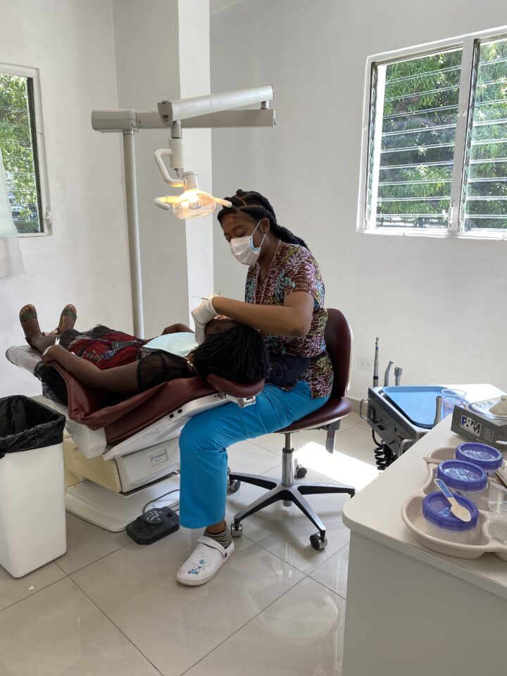 Dentist works inside a patient's mouth with the patient in a dental chair