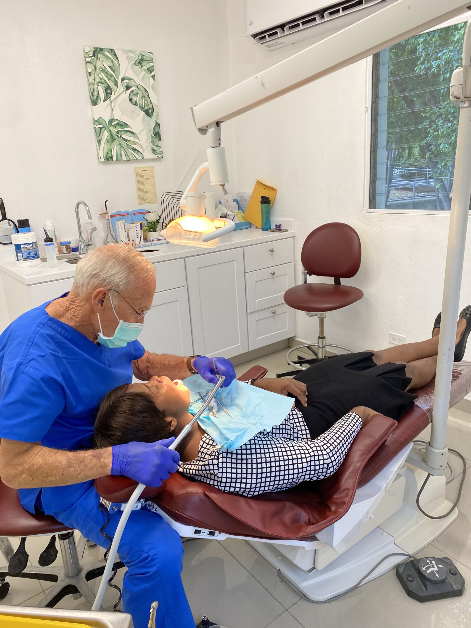 Dentist works inside a patient's mouth with the patient in a dental chair